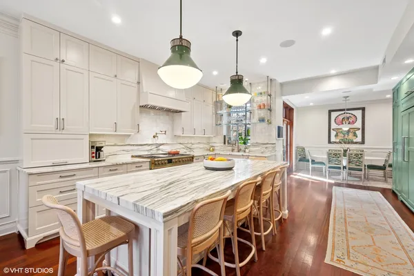 a kitchen with stainless steel appliances kitchen island granite countertop a table chairs in it and wooden floors