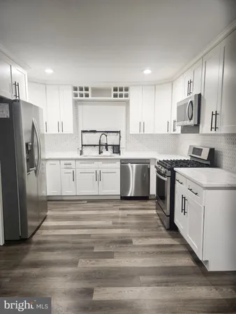 a kitchen with stainless steel appliances granite countertop a refrigerator sink and white cabinets