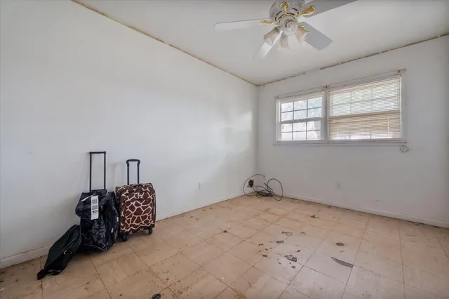 a room with chandelier fan and windows