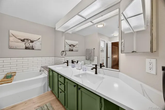 a bathroom with a double vanity sink mirror and bathtub