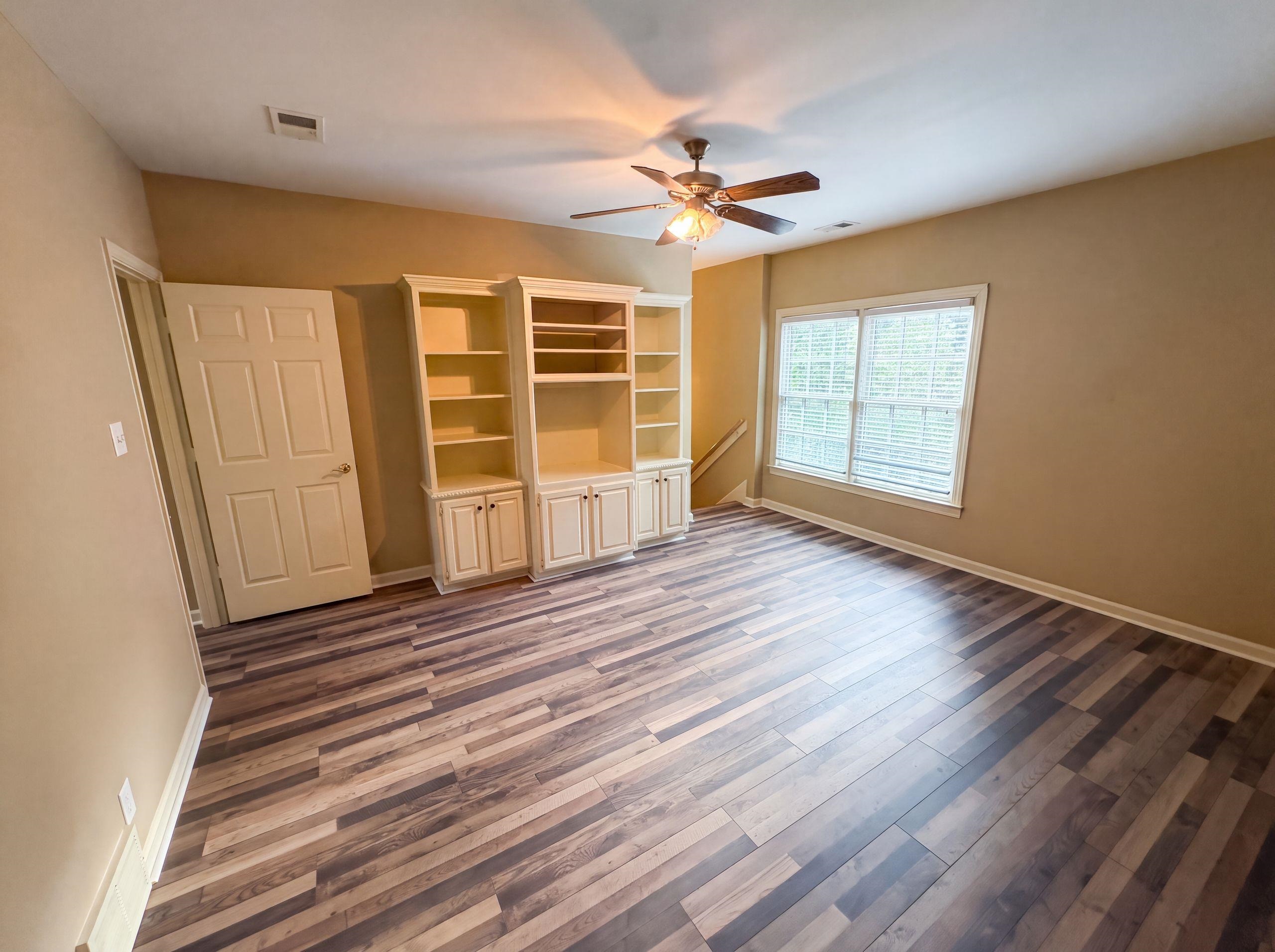 9424 Gotten Road Germantown, TN 38139 - Photo 12 of 27 Versatile room featuring wood-finish flooring, custom built-in cabinetry and shelving, a ceiling fan with integrated lighting, and a large window with blinds
