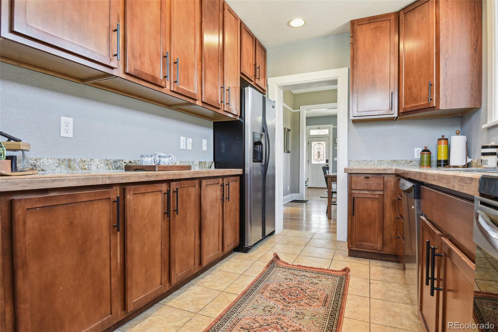 3946 Perry Street Denver, CO 80212 - Photo 9 of 27 a kitchen with stainless steel appliances granite countertop a refrigerator and wooden cabinets