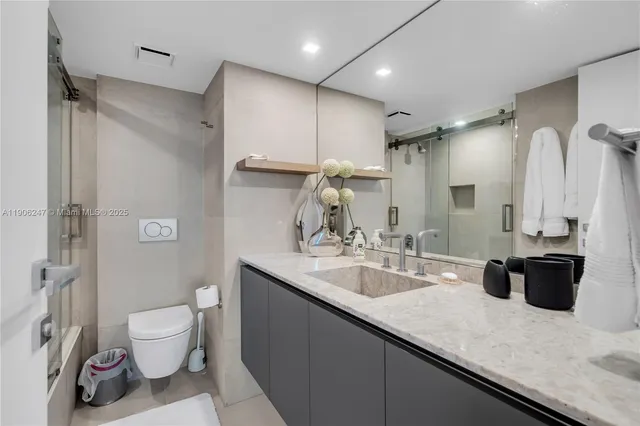 a bathroom with a granite countertop sink a toilet a mirror and shower