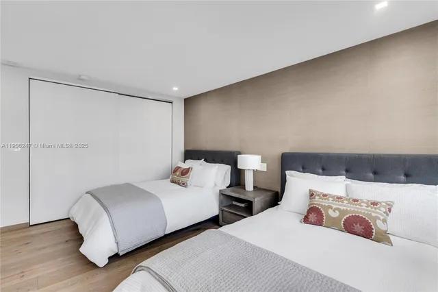 a bedroom with two beds and wooden floor