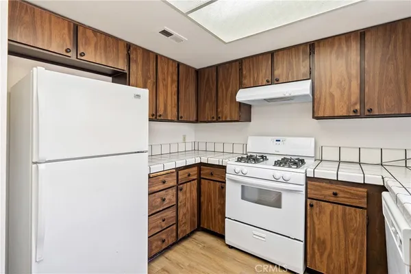 a white refrigerator freezer sitting inside of a kitchen with stainless steel appliances granite countertop wooden cabinets sink and a refrigerator