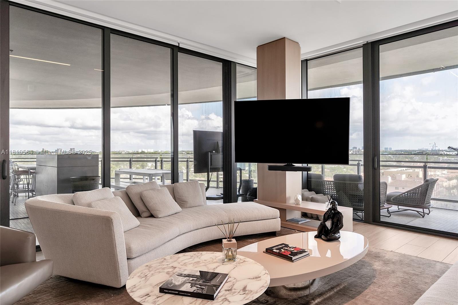 8701 Collins Avenue, Unit 905 Miami Beach, FL 33154 - Photo 6 of 80 a living room with furniture a flat screen tv and a floor to ceiling window