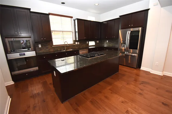 a kitchen with stainless steel appliances granite countertop a stove a refrigerator and a sink