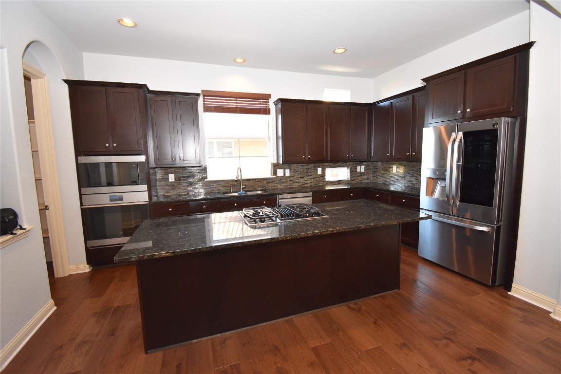 12105 Terraza Circle, Unit 67 Austin, TX 78726 - Photo 5 of 30 a kitchen with stainless steel appliances granite countertop a refrigerator a sink a stove a microwave and wooden floor