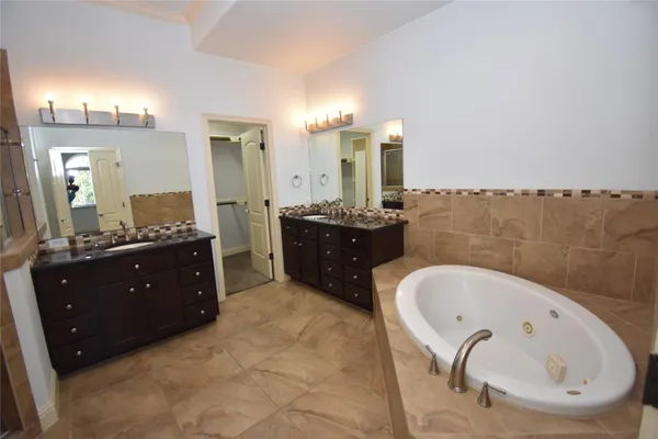 a spacious bathroom with a tub sink and mirror