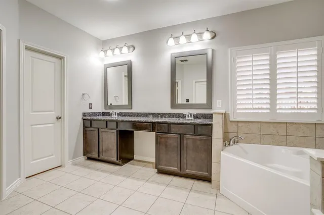 a bathroom with a granite countertop sink and a bathtub