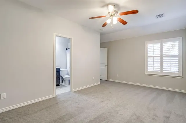 an empty room with chandelier fan and windows