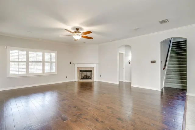 an empty room with wooden floor a kitchen view and a fireplace