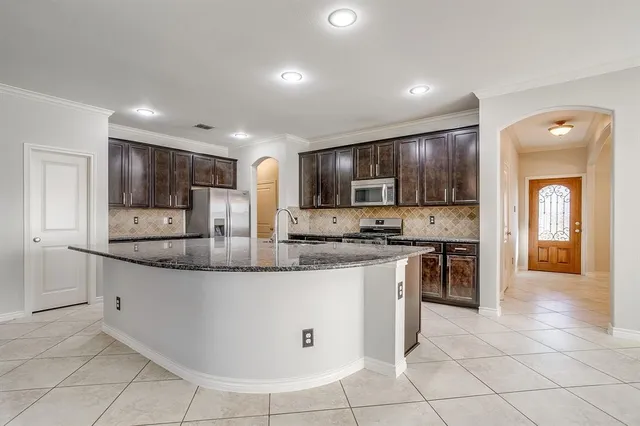 a kitchen with stainless steel appliances granite countertop a stove top oven a sink and a refrigerator