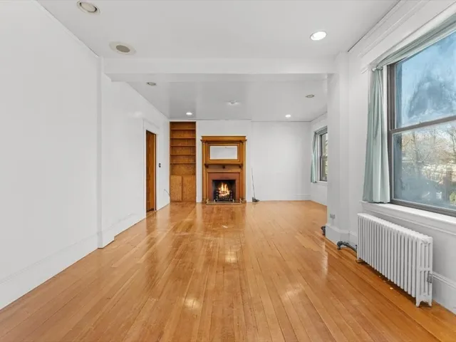 a big room with wooden floor fireplace and windows