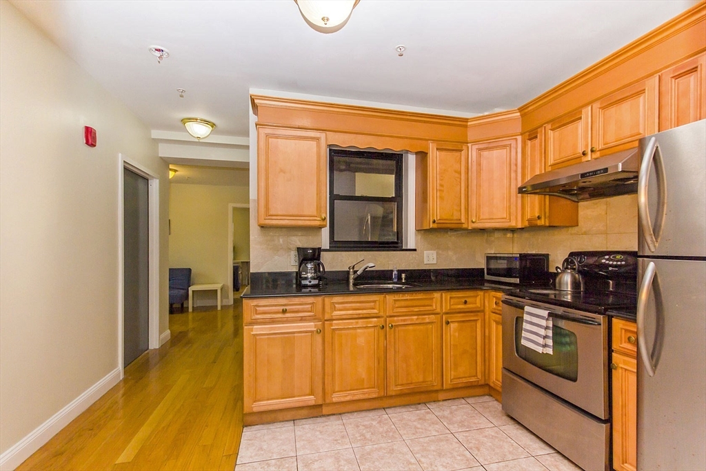 106 Tyler Street Boston, MA 02111 - Photo 3 of 16 a kitchen with stainless steel appliances granite countertop a sink and cabinets