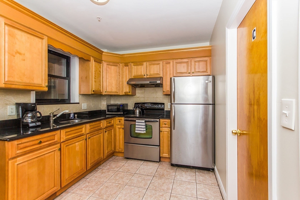 106 Tyler Street Boston, MA 02111 - Photo 4 of 16 a kitchen with stainless steel appliances granite countertop a refrigerator and a sink