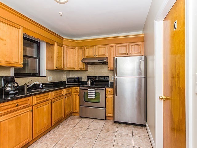 106 Tyler Street Boston, MA 02111 - Photo 5 of 16 a kitchen with a refrigerator a stove top oven and cabinets