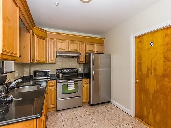 a kitchen with a refrigerator a stove top oven and cabinets