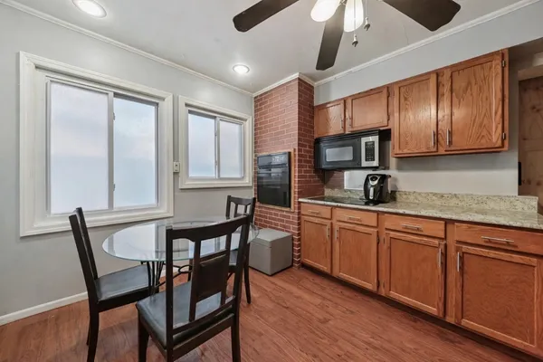 a kitchen with stainless steel appliances granite countertop a stove a sink dishwasher a dining table and chairs with wooden floor