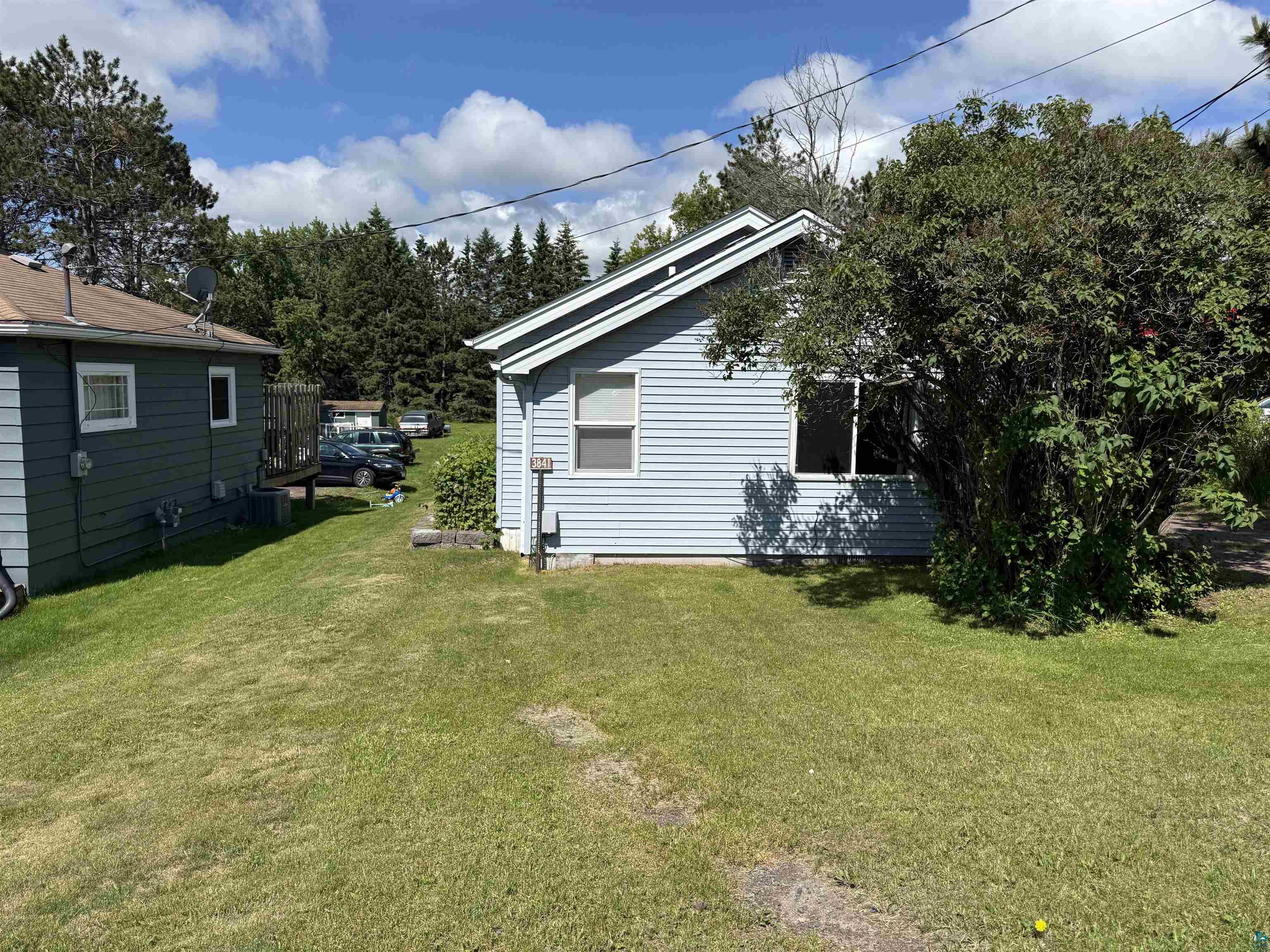 3841 Haines Road Hermantown, MN 55811 - Photo 11 of 11 Light blue horizontal siding exterior with white trim windows and a prominent mature shrub
