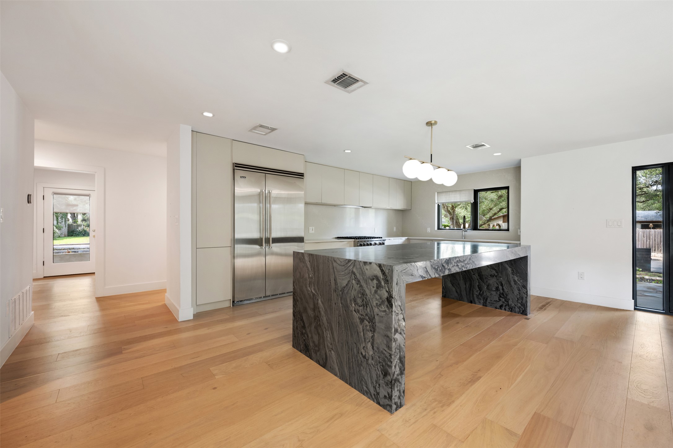 8900 Point W Drive Austin, TX 78759 - Photo 18 of 40 A well-appointed kitchen showcasing a captivating waterfall island and gleaming hardwood floors.