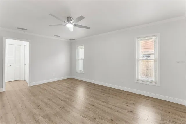 a view of an empty room with wooden floor and a window