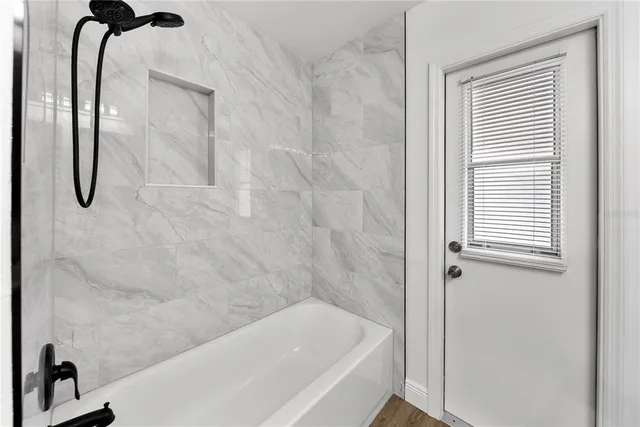 a bathroom with a tub shower and a window