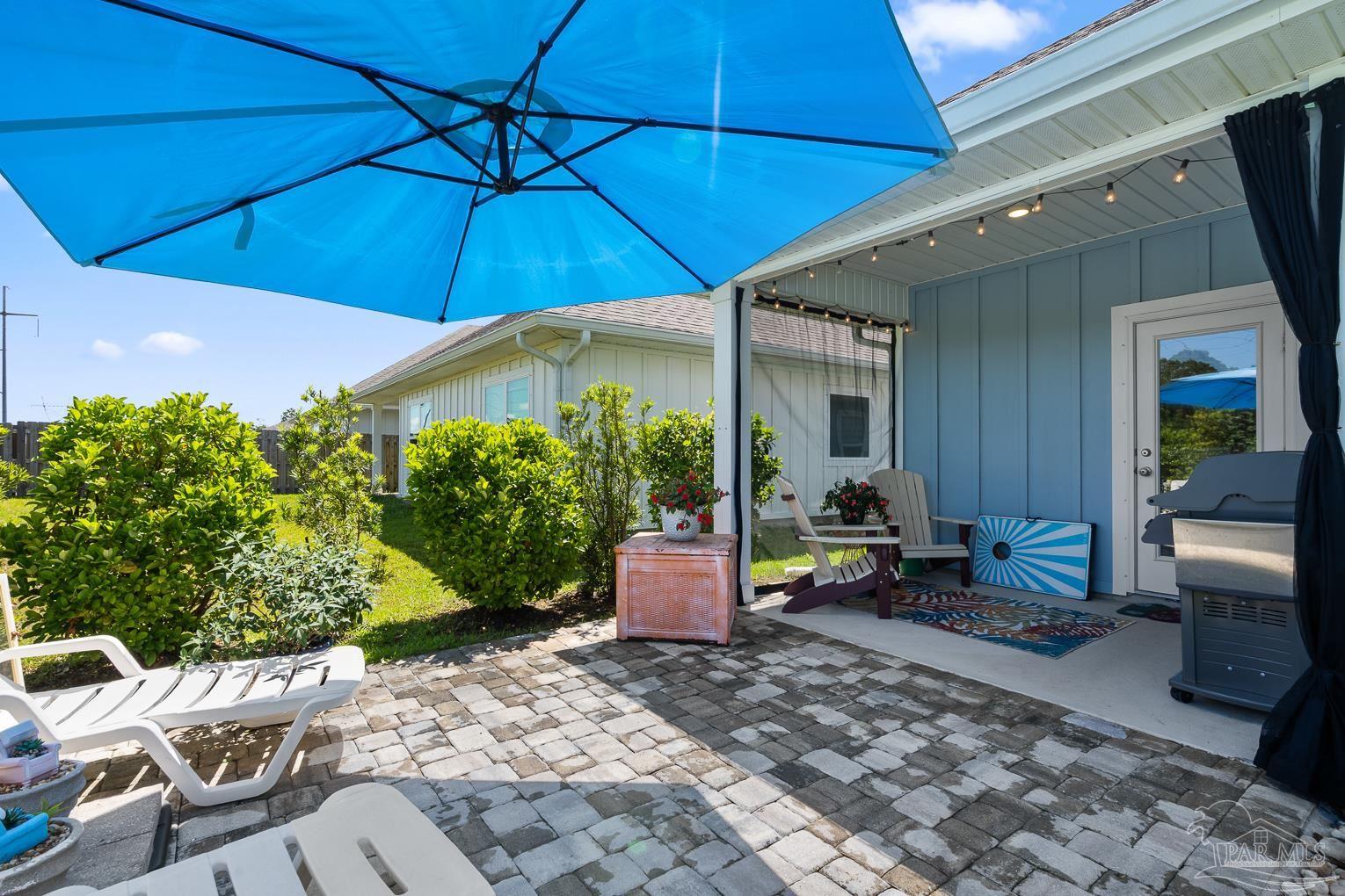 5773 Danbury Boulevard Pace, FL 32571 - Photo 30 of 34 a patio with a table and chairs under an umbrella