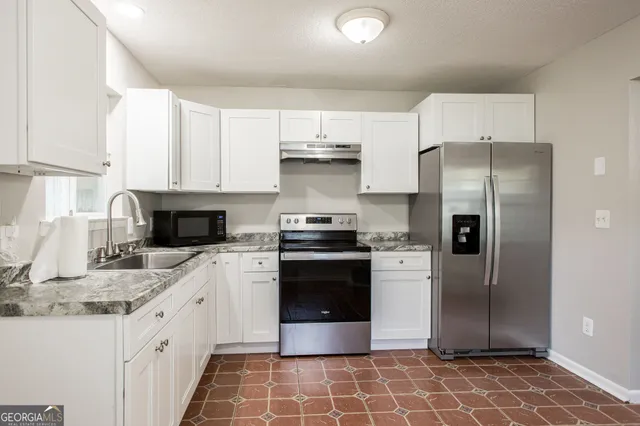 a kitchen with stainless steel appliances granite countertop a refrigerator and a stove