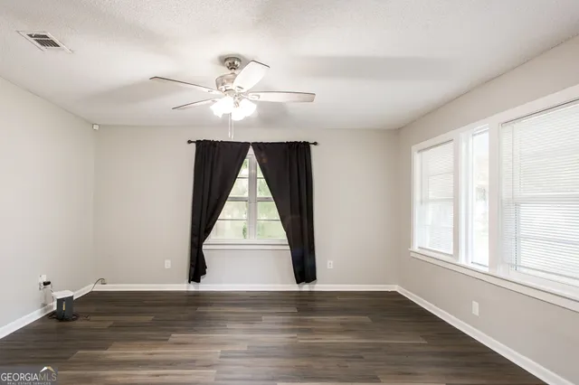 an empty room with wooden floor cabinet and windows