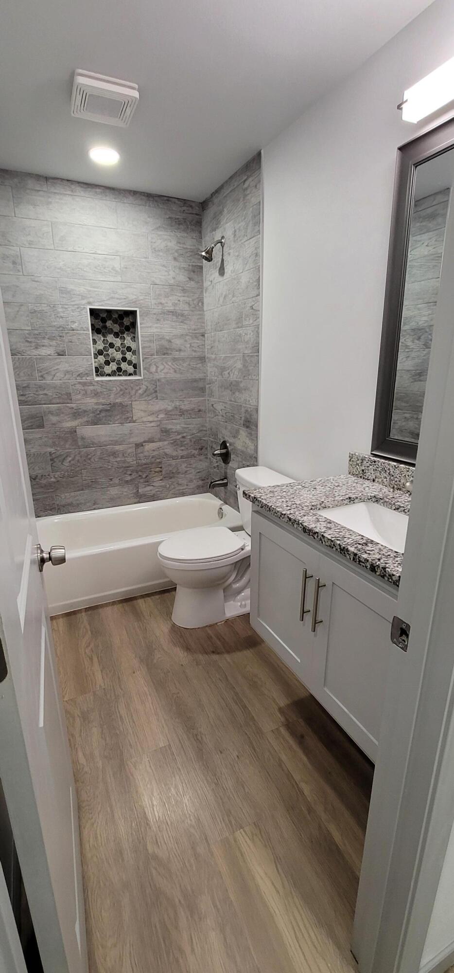 2110 88th Street Lubbock, TX 79423 - Photo 19 of 22 a bathroom with a granite countertop sink a toilet a mirror and bathtub