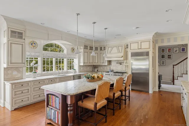 a kitchen with stainless steel appliances granite countertop a stove a refrigerator a oven a sink a dining table and chairs with wooden floor