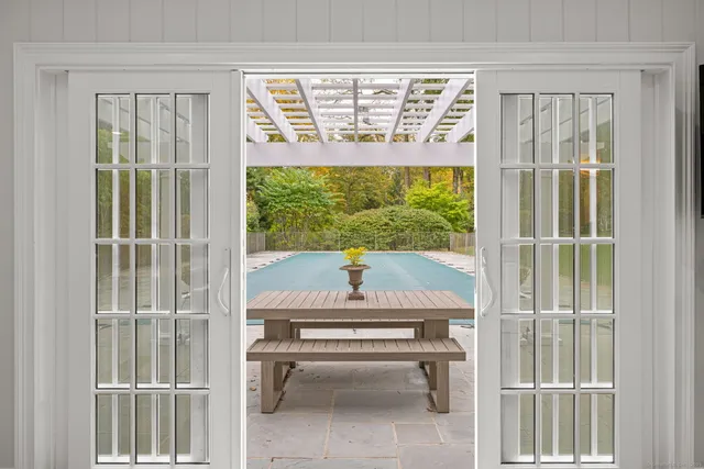 a view of a swimming pool with lawn chairs and a large tree