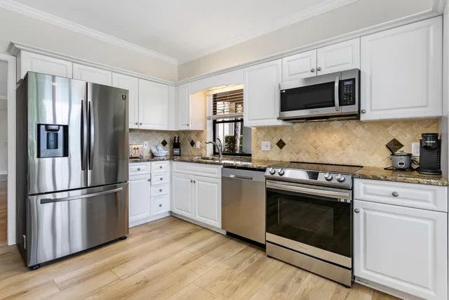 a kitchen with cabinets stainless steel appliances and wooden floor