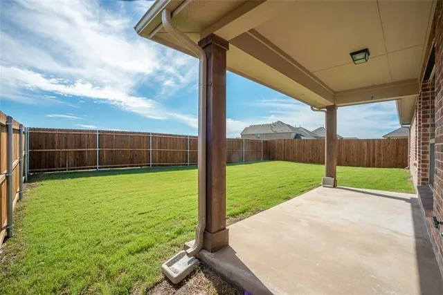 a view of a backyard with grass & a ceiling fan