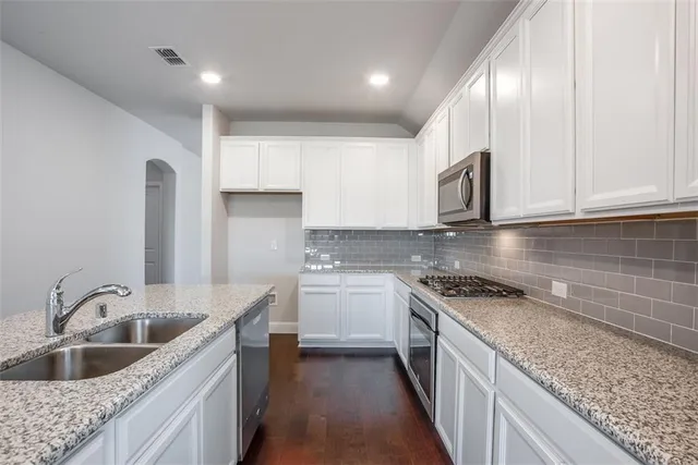 a kitchen with stainless steel appliances granite countertop a sink stove and cabinets
