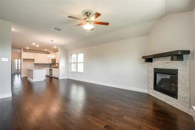 an empty room with wooden floor fireplace and windows