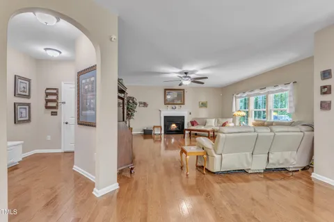 a kitchen with stainless steel appliances granite countertop a stove top oven a sink a refrigerator and white cabinets with wooden floor