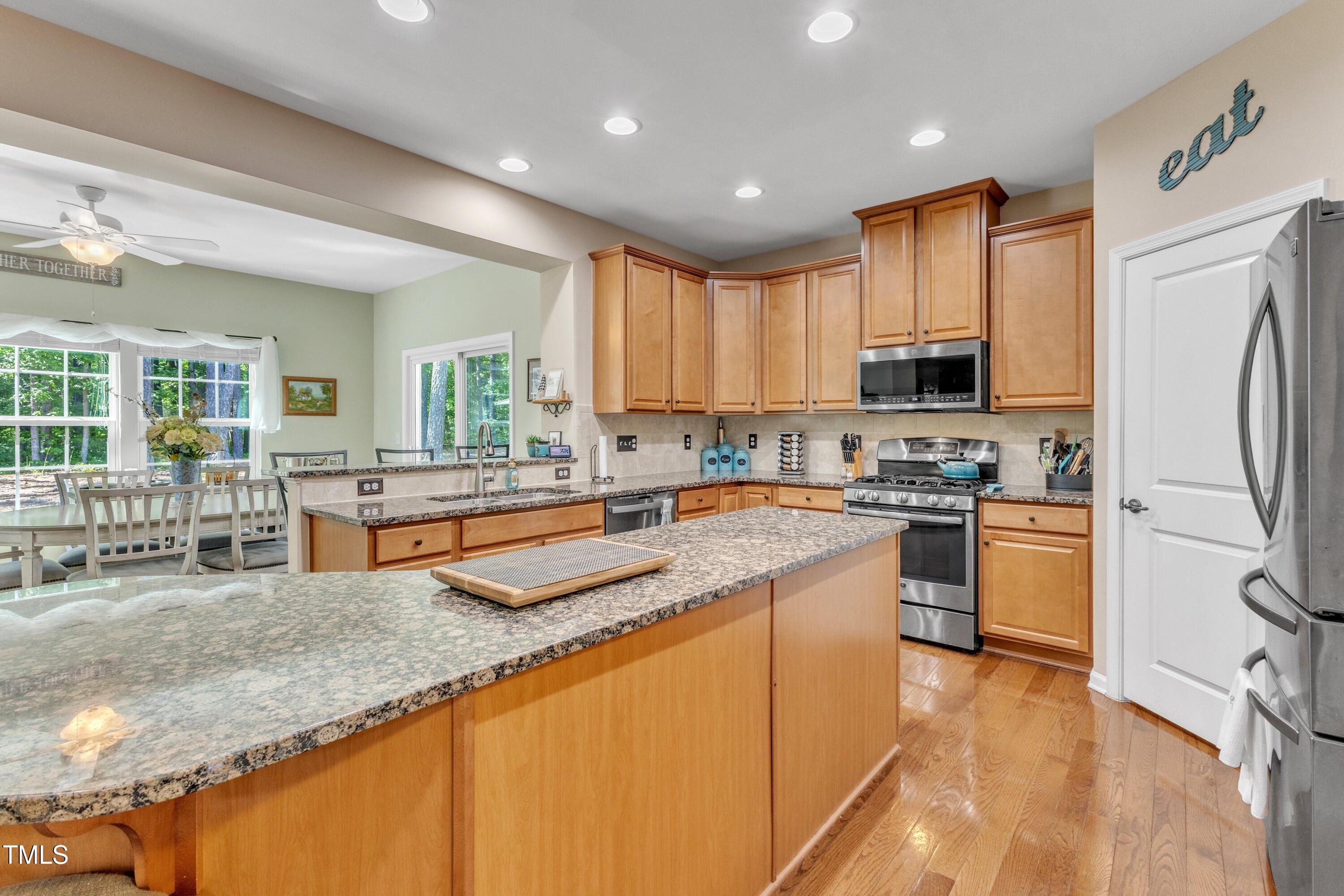 533 Opposition Way Wake Forest, NC 27587 - Photo 27 of 87 a kitchen with stainless steel appliances granite countertop a stove top oven a sink a refrigerator and white cabinets with wooden floor