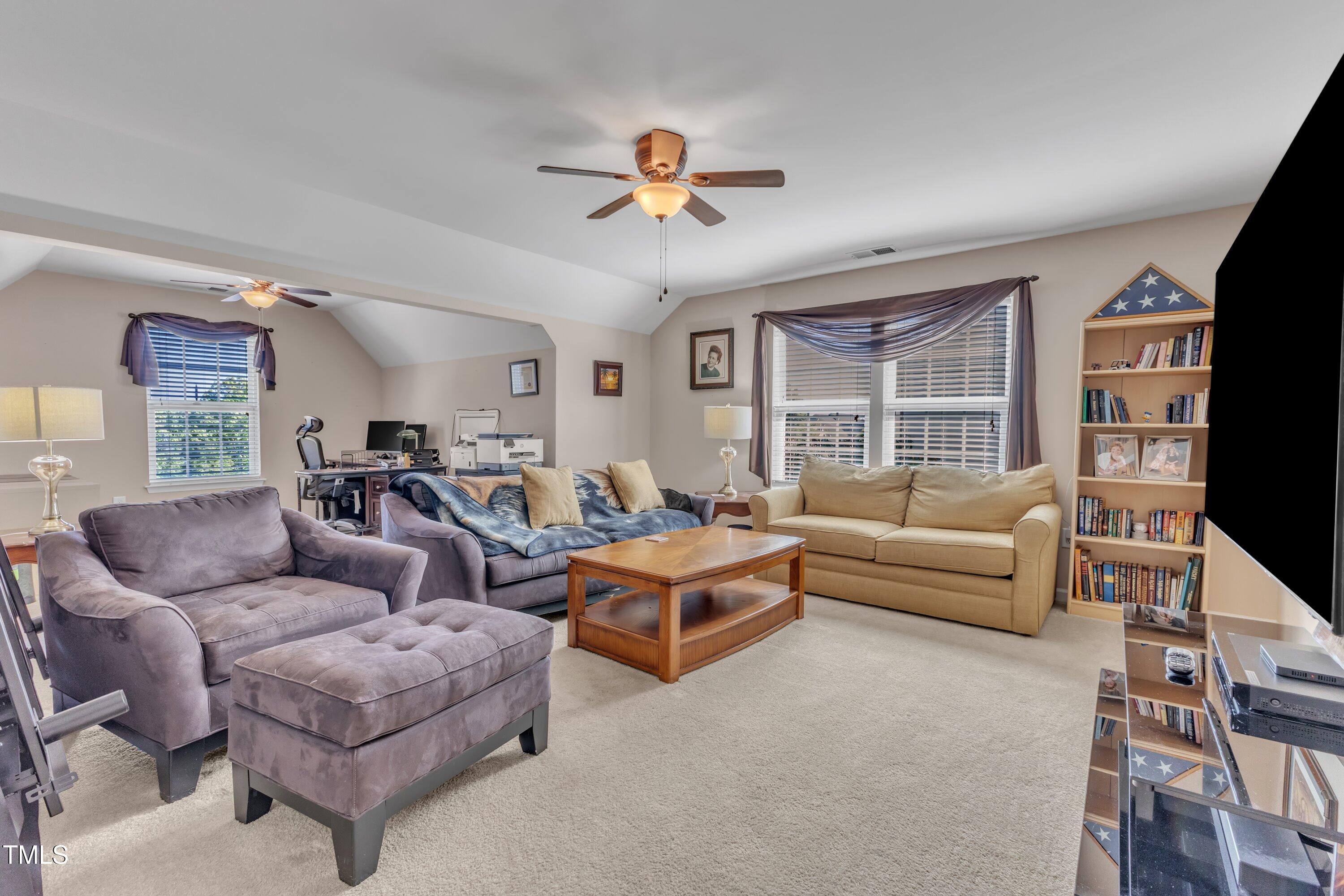 533 Opposition Way Wake Forest, NC 27587 - Photo 59 of 87 a living room with furniture a ceiling fan a fireplace and a window