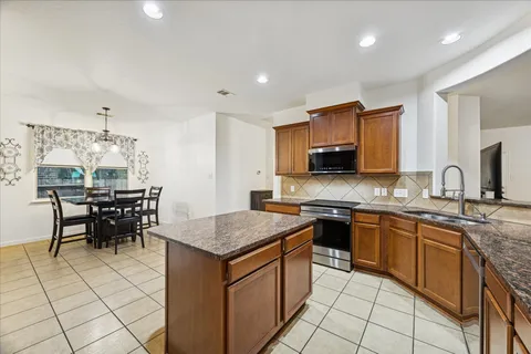 a kitchen with stainless steel appliances granite countertop a stove top oven a sink dishwasher a dining table and chairs with wooden floor