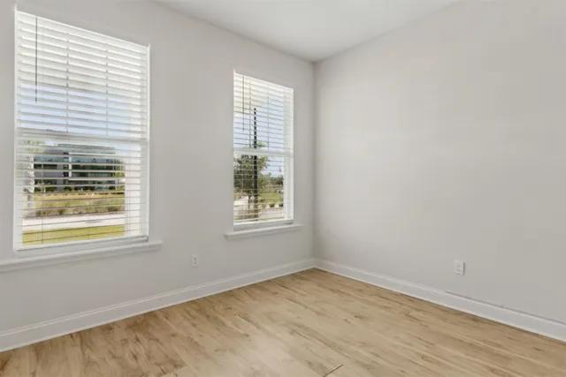 a view of an empty room with wooden floor and closet