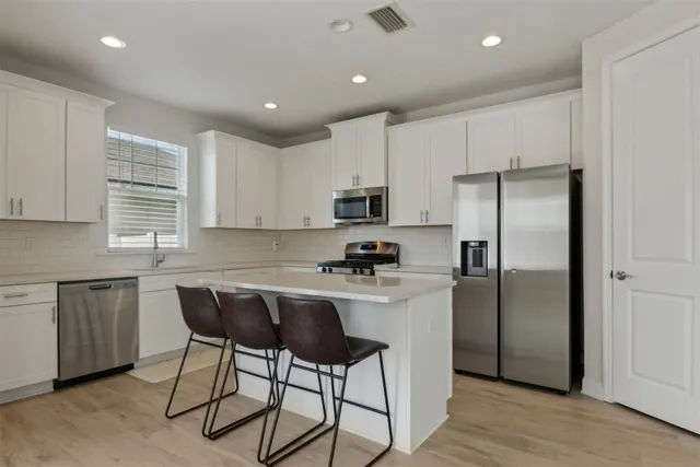 a kitchen with kitchen island a refrigerator stove microwave and cabinets