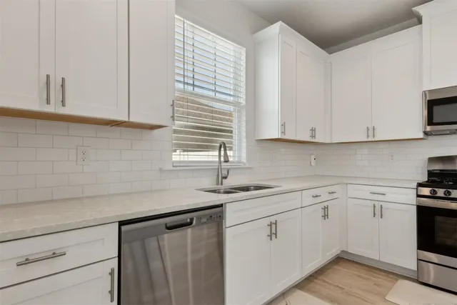 a kitchen with stainless steel appliances granite countertop white cabinets and a sink