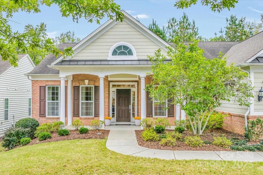 a view of a brick house with potted plants and a large tree