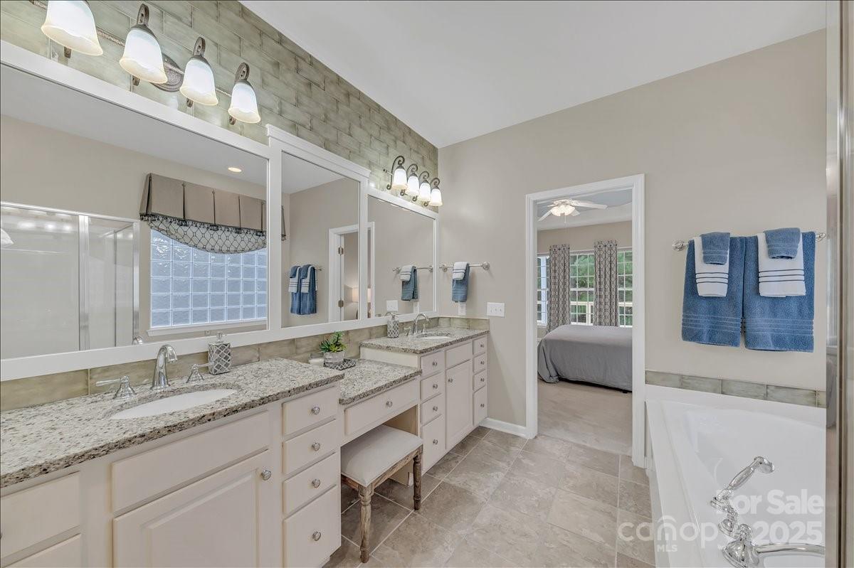 51225 Daffodil Court Fort Mill, SC 29707 - Photo 27 of 45 a spacious bathroom with a granite countertop double vanity sink a large mirror and a bathtub