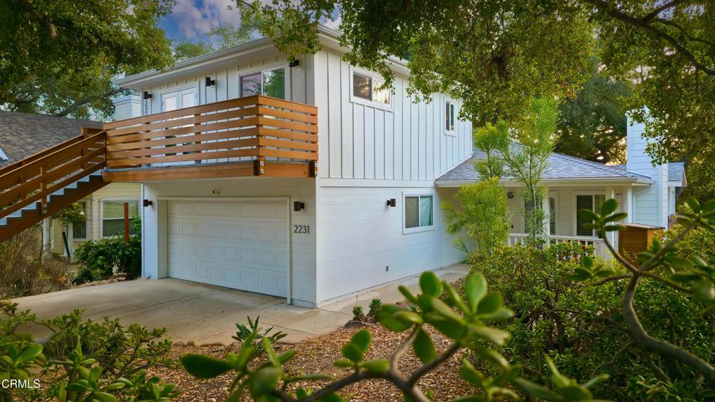 a view of a house with potted plants and a large tree