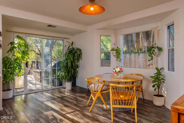 a dining room with furniture potted plants and wooden floor