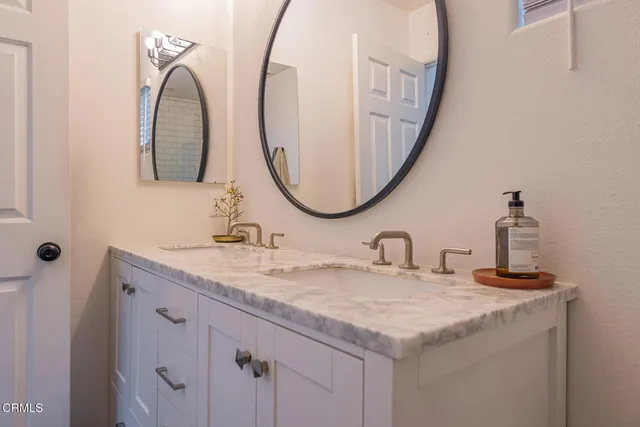 a bathroom with a granite countertop sink and a mirror
