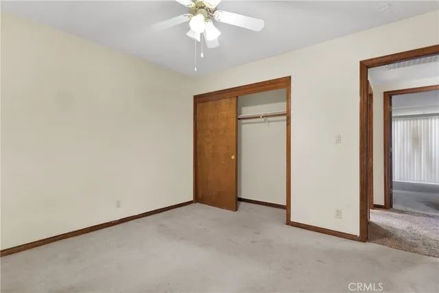 an empty room with a chandelier fan and closet area